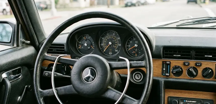 Close-up of an original Mercedes W116 dashboard with thin steering wheel and analog controls