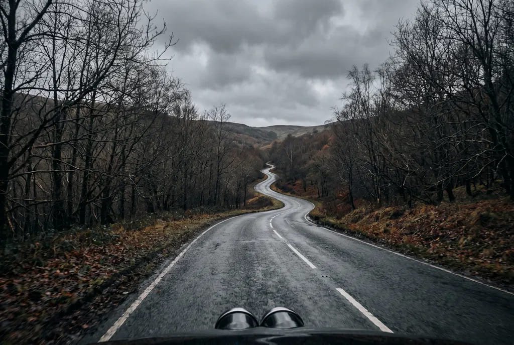 The undocumented road – a drive taken for no one Rear view from a car looking back along an empty damp winding road in autumn, no other vehicles