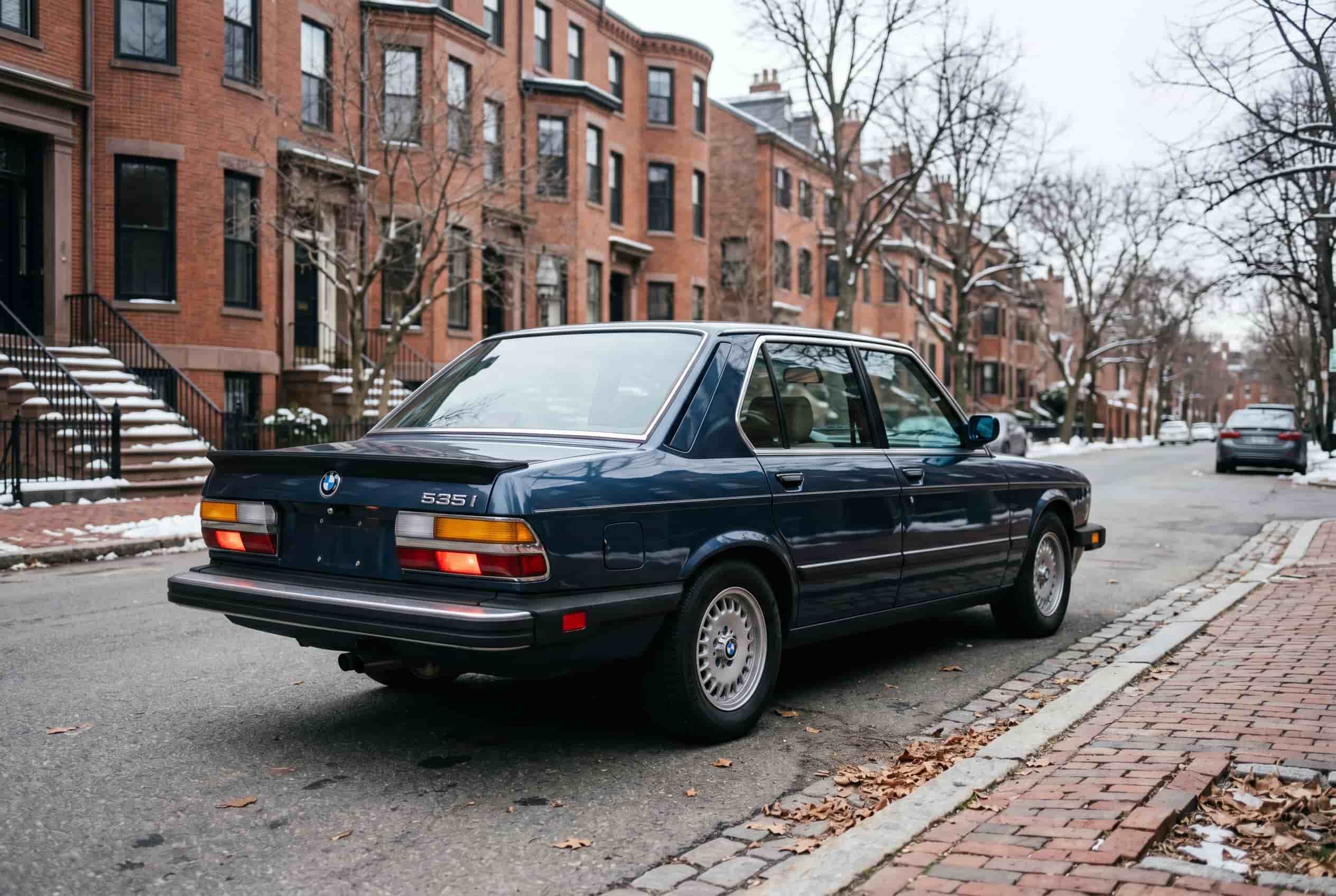 The last intellectual BMW – E28 535i in Boston 1986 BMW E28 535i in dark blue parked on a Boston residential street with bare winter trees and brick sidewalk