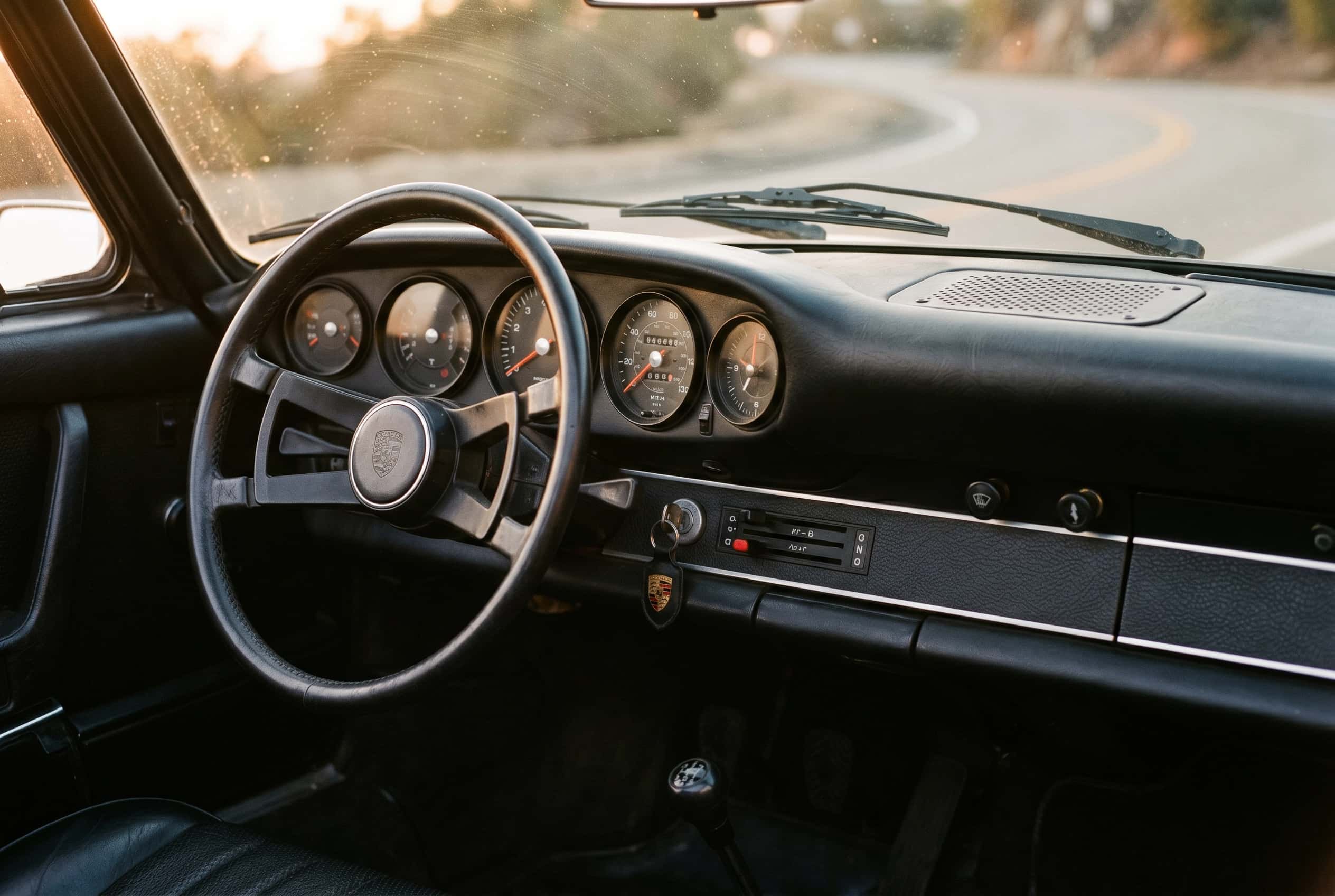 1970s Porsche 911 dashboard with five round instruments and left-side ignition, warm evening light
